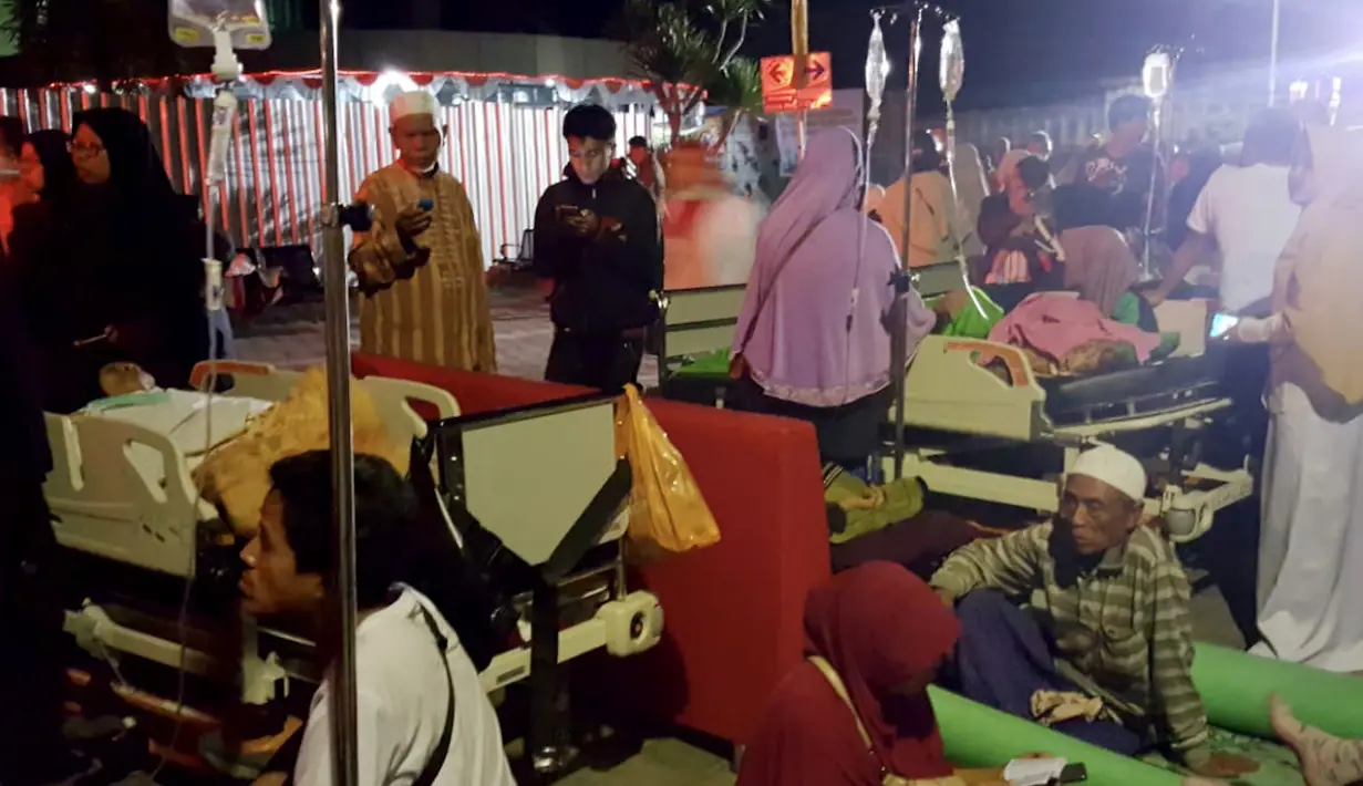 Pasien berada diluar rumah sakit saat gempa mengguncang Lombok Utara, NTB Minggu malam (5/8). BMKG menyatakan, potensi tsunami akibat gempa 7 SR, telah terdeteksi di Carik pada pukul 18.48 WIB. (AFP Photo/Rita Siswati)