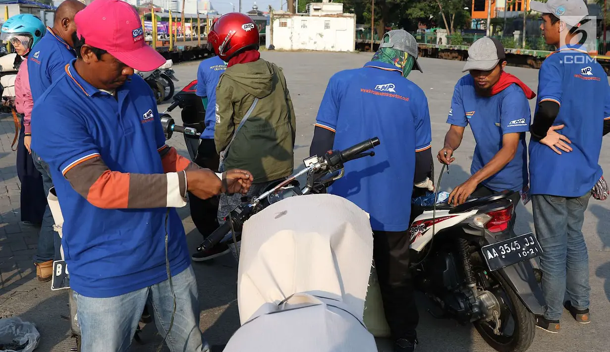 Petugas mengemas sepeda motor untuk diangkut dengan kereta api Stasiun Kampung Bandan, Jakarta, Senin (11/6). Program mudik gratis ini digagas Kemenhub tersebut melayani pengiriman ke beberapa daerah di Pulau Jawa. (Liputan6.com/Immanuel Antonius)