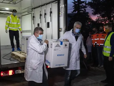 Petugas kesehatan membawa kotak berisi vaksin COVID-19 dari Pfizer saat tiba untuk pertama kalinya di Kryoneri village, dekat Athena, Yunani, Sabtu (26/12/2020). Gelombang pertama vaksin untuk melawan COVID-19 tiba di Yunani. (AP Photo/Yorgos Karahalis)
