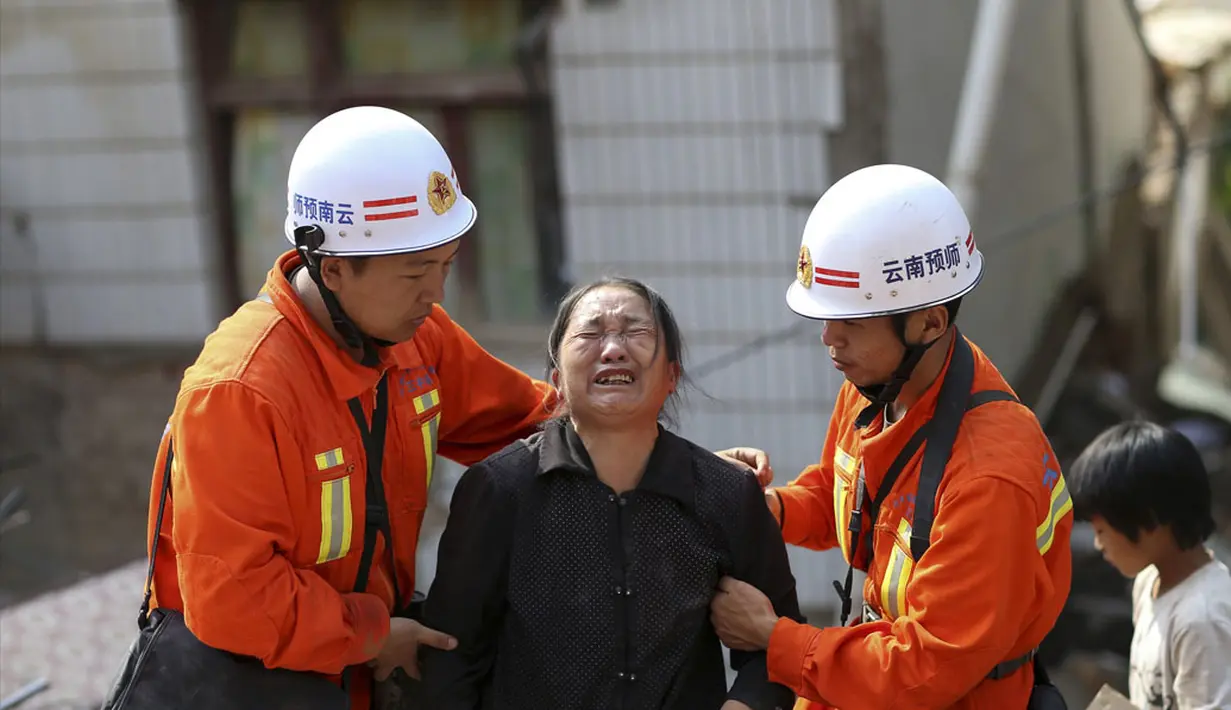 Petugas penyelamat membantu seorang wanita yang menangis di zona gempa di Longtoushan, provinsi Yunan, Tiongkok, (6/8/2014). (REUTERS/Stringer)