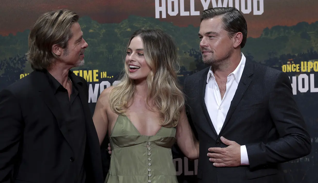 Aktris Margot Robbie berbincang dengan Leonardo DiCaprio dan Brad Pitt saat menghadiri pemutaran perdana film 'Once Upon A Time in Hollywood' di Berlin (1/8/2019). Margot Robbie tampil elegan tanpa perhiasan dan aksesori sesuai dengan suasana musim panas yang melanda Eropa. (AP Photo/Michael Sohn)