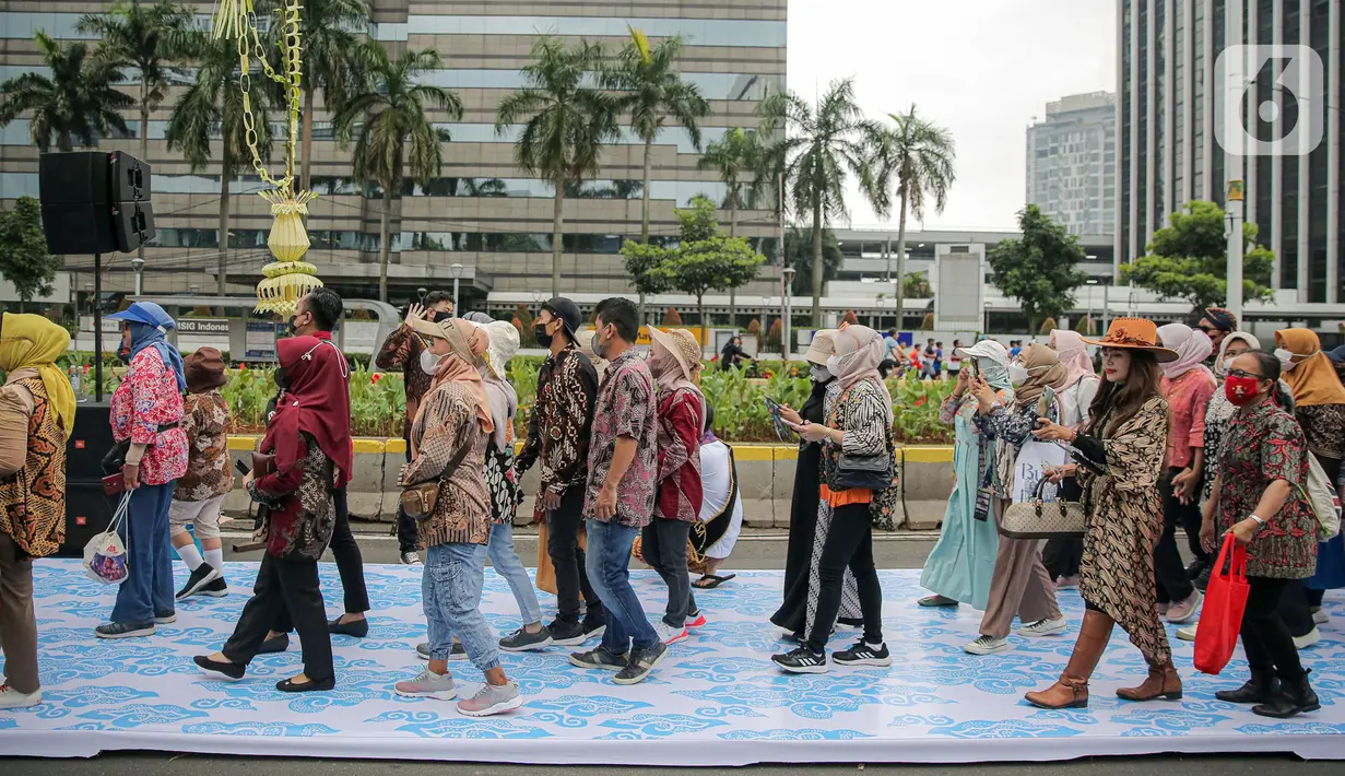 Sejumlah orang yang mengenakan batik berjalan di catwalk sepanjang Jalan Jenderal Sudirman, Jakarta, Minggu (2/10/2022). Kegiatan yang diikuti ratusan orang ini diselenggarakan oleh Bank Mandiri untuk menyambut Hari Batik Nasional yang jatuh setiap tanggal 2 Oktober 2022. (Liputan6.com/Faizal Fanani)