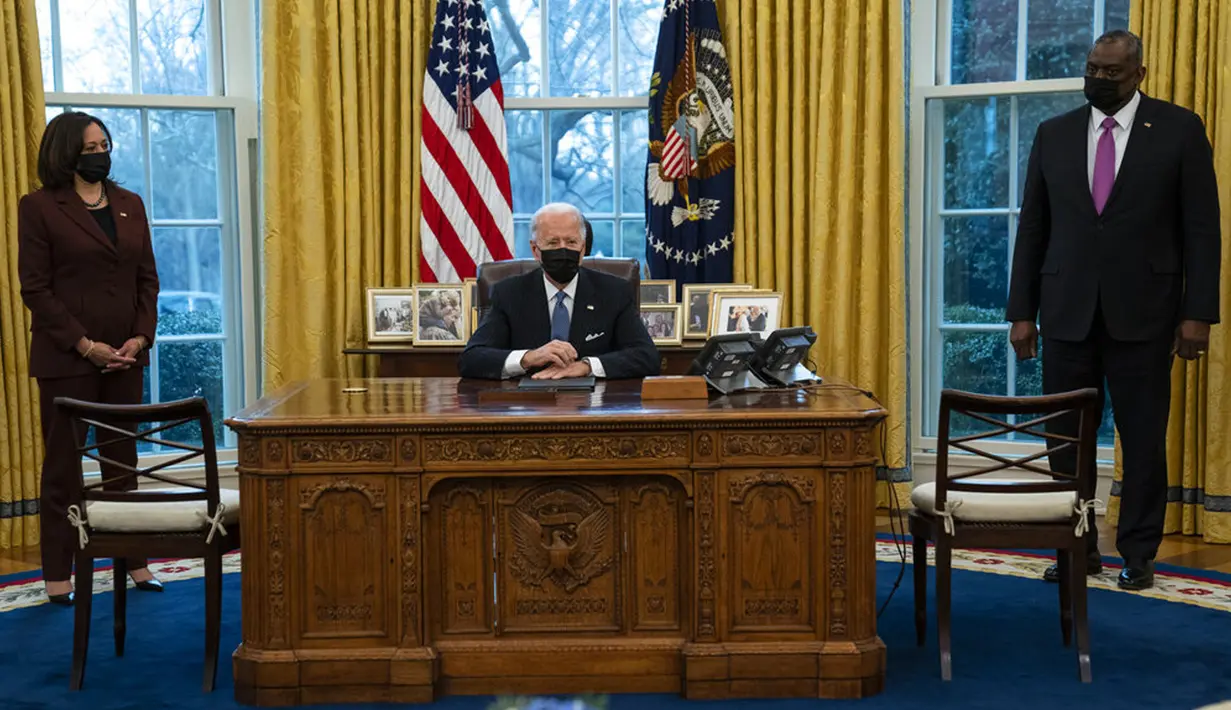 Wapres Kamala Harris dan Menhan Lloyd Austin mendengarkan Presiden AS Joe Biden berbicara sebelum menandatangani Perintah Eksekutif yang membatalkan larangan bagi transgender untuk masuk militer AS pada era Donald Trump, Kantor Oval Gedung Putih, Washington, Senin (25/1/2021). (AP Photo/Evan Vucci)