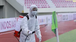 Petugas menyemprot bendera sepak pojok dengan disinfektan sebelum pertandingan antara Persikabo 1973 melawan Arema FC pada laga Piala Menpora di Stadion Manahan, Solo, Minggu (21/3/2021). (Bola.com/M Iqbal Ichsan)