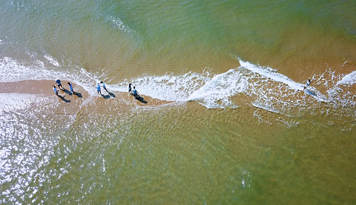 Foto dari udara pada 19 Juni 2020 menunjukkan wisatawan berjalan di sebuah gosong pasir di Desa Qixia, Wilayah Dongshan, Provinsi Fujian, China tenggara. Menjadi objek wisata populer karena bentuknya yang seperti tulang ikan, gosong pasir ini telah menarik banyak wisatawan. (Xinhua/Wei Peiquan)