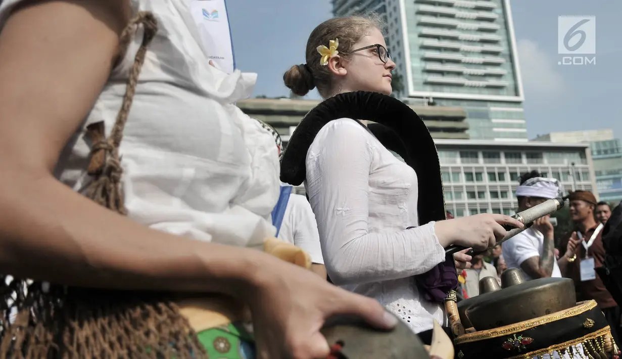 Mahasiswa internasional dengan balutan pakaian adat Indonesia bermain gamelan saat pawai kelulusan beasiswa Kemendikbud di car free day (CFD), Jakarta, Minggu (6/5). (Merdeka.com/Iqbal Nugroho)
