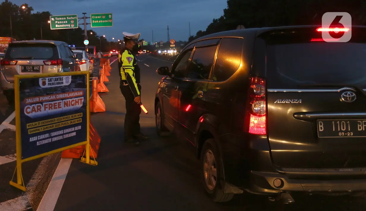 Petugas dari Polres Bogor memasang rambu penutupan jalan di pintu keluar Tol Gadog, Bogor, Sabtu (31/12/2022). Penutupan jalan jalur Puncak Bogor untuk gelaran Car Free Night dimulai sejak pukul 18.00 WIBdan dibuka kembali esok pagi pukul 06.00 WIB. (merdeka.com/Arie Basuki)