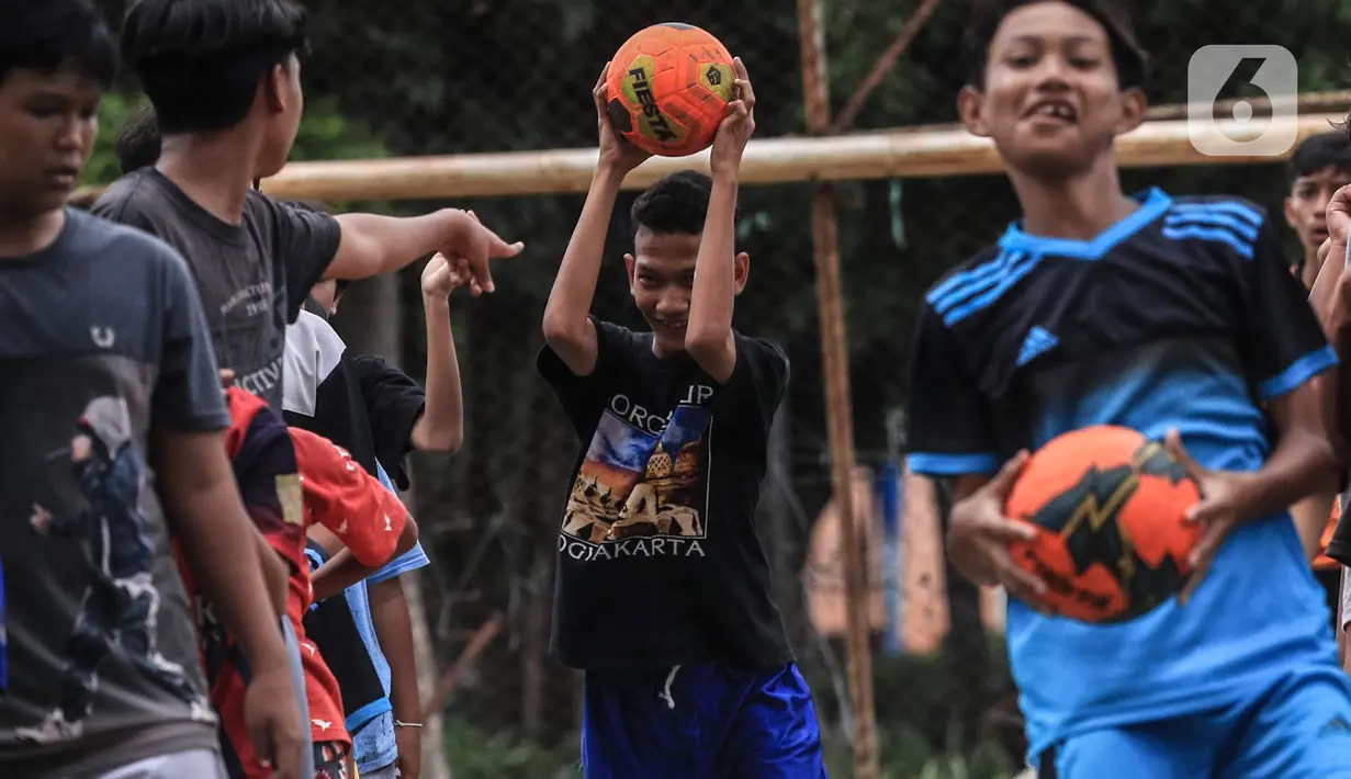Anak-anak berlatih sepak bola di lapangan samping Banjir Kanal Barat (BKB), Jakarta, Kamis (7/1/2020). Revitalisasi jalur hijau di sepanjang aliran BKB menyulap kawasan kumuh menjadi tempat interaktif warga sekitar yang dilengkapi fasilitas bermain, seperti lapangan futsal. (Liputan6.com/Johan Tallo