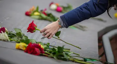 Kelli Muster dari Santa Rosa, California meletakkan bunga mawar merah di Columbine Memorial di Clement Park pada peringatan 25 tahun penembakan di sekolah tersebut pada 20 April 2024 di Littleton, Colorado. (Marc Piscotty/Getty Images North America/Getty Images via AFP)