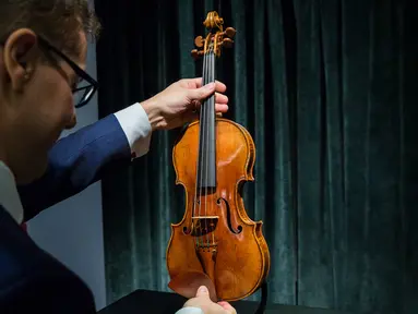 Perwakilan dari Sotheby Hong Kong memegang biola langka 1684 buatan Antonio Stradivari saat diperkenalkan di hadapan pers di Hong Kong (21/2). Pelelangan biola ini akan digelar pada 28 Maret 2017 mendatang di London. (AFP Photo / Isaac Lawrence)