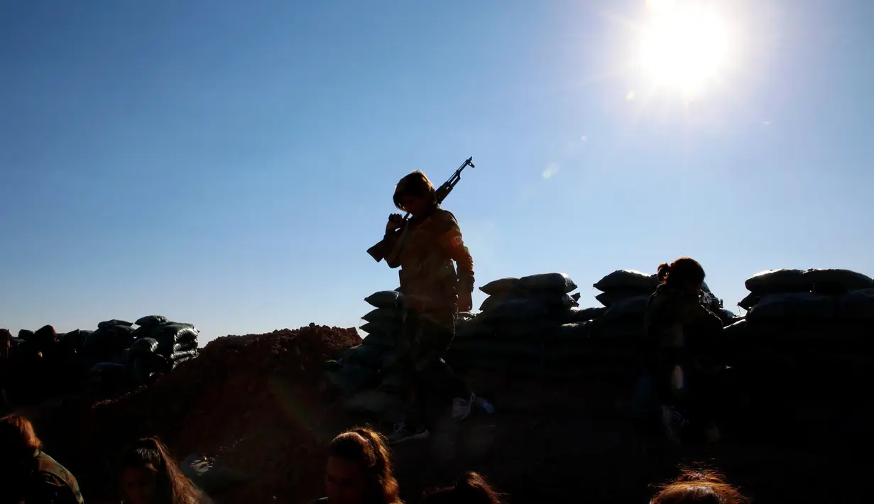 Seorang pejuang perempuan Iran-Kurdi membawa senjatanya saat bertempur melawan kelompok ISIS di Bashiqa, dekat Mosul, Irak, Kamis (3/11). Awalnya, para wanita Kurdi hanya sebagai pasukan medis, komunikasi dan administrasi. (Reuters/Ahmed Jadallah)