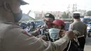 Anggota polisi dari Polsek Parung membantu memasangkan masker kepada pengendara sepeda motor di depan Polsek Parung, Kabupaten Bogor, Jawa Barat, Rabu (2/9/2020). Pembagian masker gratis setiap usai apel ini inisiatif anggota sejak masa pandemi COVID-19. (merdeka.com/Dwi Narwoko)