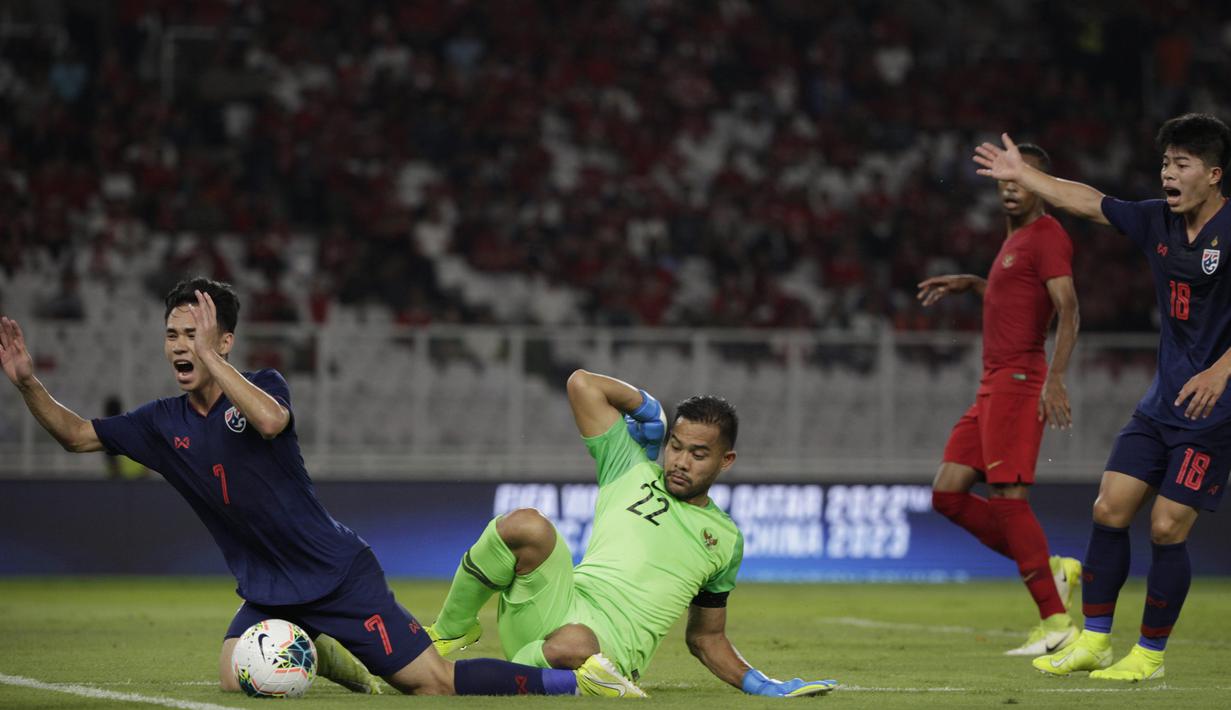 Kiper Timnas Indonesia, Andritany Ardhiyasa, menjatuhkan gelandang Thailand, Supachok Sarachat pada laga Kualifikasi Piala Dunia 2022 di SUGBK, Jakarta, Selasa (10/9). Indonesia kalah 0-3 dari Thailand. (AFP/Vitalis Yogi Trisna)
