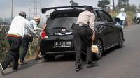 Personel Polsek Ibun membantu mendorong kendaraan roda empat yang tak kuat menanjak di kawasan Kamojang, Kabupaten Bandung. (Liputan6.com/Huyogo Simbolon)