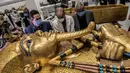 Para arkeolog merestorasi sarkofagus atau peti mati emas Firaun Tutankhamun di laboratorium restorasi Grand Egyptian Museum (GEM), Giza, Mesir, Senin (13/4/2020). Firaun Tutankhamun merupakan Raja Mesir Kuno yang memerintah antara tahun 1342-1325 SM. (Khaled DESOUKI AFP)