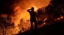 Seorang warga berdiri saat mencoba memadamkan api yang menyebar di Desa Akcayaka, Milas, Provinsi Mugla, Turki, Jumat (6/8/2021). Delapan orang tewas dan puluhan lainnya dirawat di rumah sakit dalam kebakaran hutan di Turki. (Yasin AKGUL/AFP)