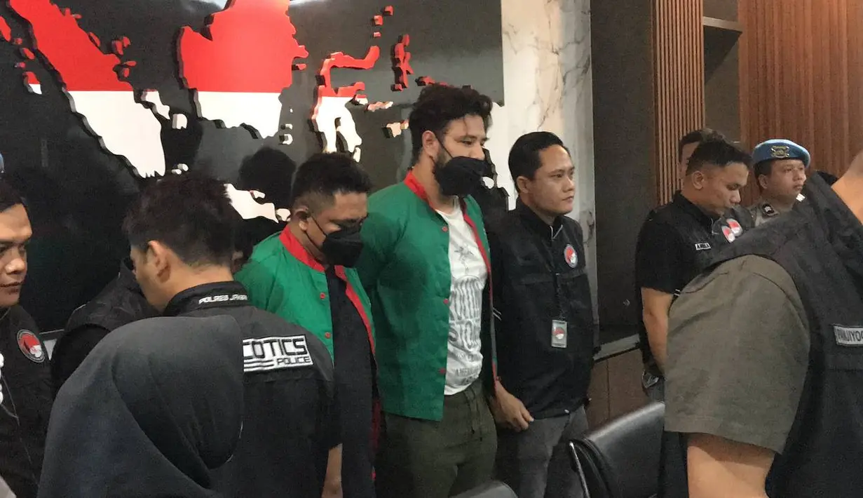 Saat dihadirkan dalam jumpa pers, Jumat (15/12) sekitar pukul 13.30 WIB Ammar melangkah tegap dengan tangan diborgol di belakang. Tampak beberapa polisi mengawalnya. Tersangka AH sebagai pemasok ke Ammar juga dihadirkan. [Foto: KapanLagi.com/Dadan Eka Purnama]