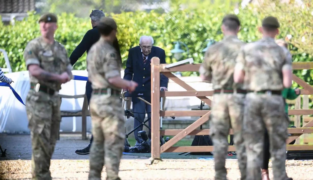 Personel militer menyambut veteran Perang Dunia II Kapten Tom Moore (99) di kebunnya di Marston Moretaine, London, 16 April 2020. Menjelang ulang tahunnya ke-100, Moore mengumpulkan donasi lebih dari 16 juta dolar untuk sumbangan bagi tenaga kesehatan yang menangani Covid-19. (Joe Giddens/PA via AP)