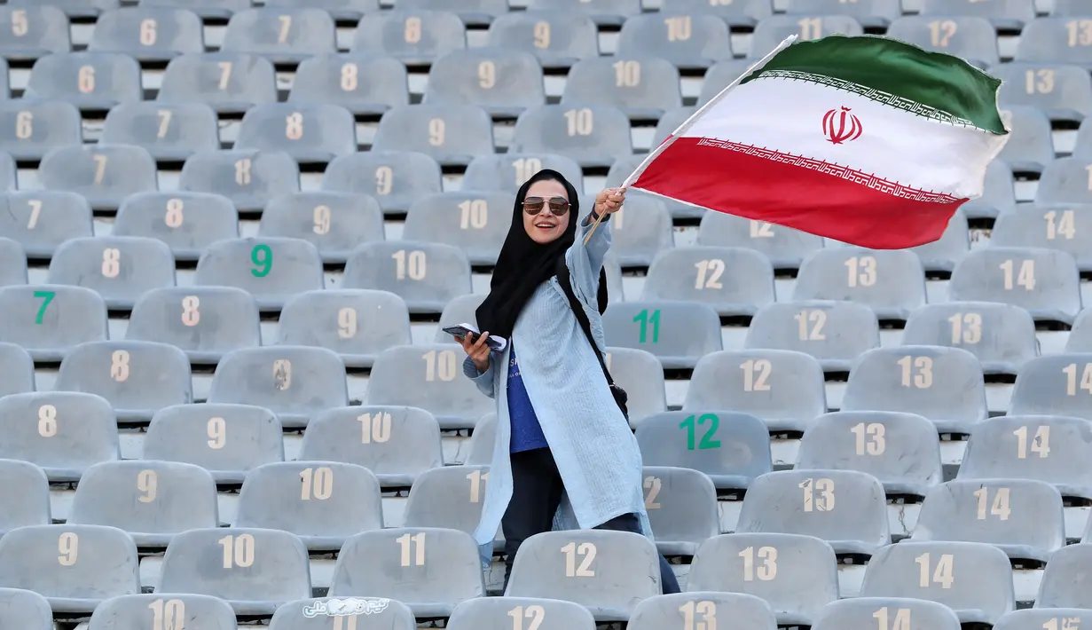 Wanita Iran mengibarkan bendera negaranya saat akan menyaksikan laga kualifikasi Piala Dunia 2022 antara Iran dengan Kamboja di Stadion Azadi, Teheran, Iran, Kamis (10/10/2019). Wanita Iran akhirnya diizinkan menonton bola dalam stadion setelah 38 tahun dilarang. (AP Photo/Vahid Salemi)