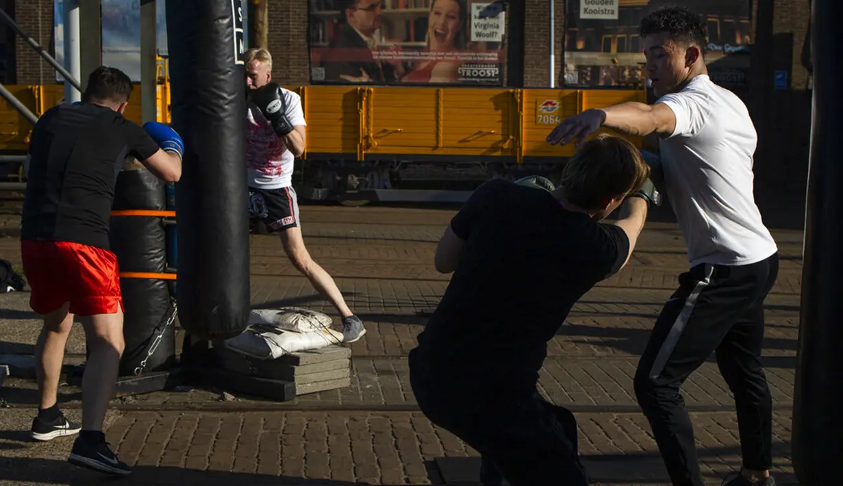 Seorang guru (kanan) memberikan pelajaran kickboxing dengan menjaga jarak 1,5 meter mengikuti peraturan protokol kesehatan virus corona COVID-19 pemerintah Belanda saat mereka berlatih di luar ruangan di Amsterdam, Belanda, Selasa (30/3/2021). (AP Photo/Peter Dejong)