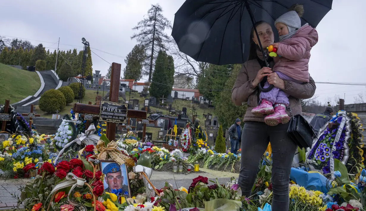 Tetiana Rurak (25) mengunjungi makam suaminya yang merupakan seorang tentara, Volodymyr Rurak, bersama putrinya yang berusia satu setengah tahun setelah suaminya itu terbunuh dalam perang dengan Rusia di pemakaman Lychakiv, Lviv, Ukraina, Selasa (5/4/2022). (AP Photo/Nariman El-Mofty)