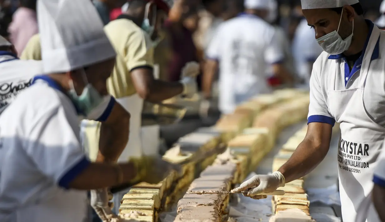 Pembuat roti dan koki menyelesaikan kue sepanjang 6,5 km untuk kue terpanjang dunia, di Thrissur di negara bagian Kerala, India selatan (15/1/2020). Dibutuhkan 12 ribu kilogram gula dan tepung dan menghabiskan waktu lebih dari empat jam untuk membuat kue terpanjang itu. (AFP/Arun Sankar)