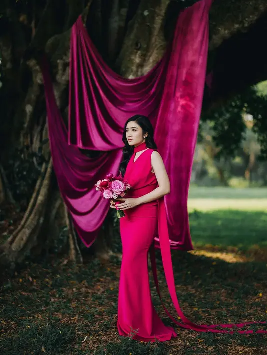 Gaun panjang berwarna fuchsia mencolok yang dikenakan Febby memiliki potongan anggun dan warna yang senada dengan dekorasi. [@terralogical @leurafilm].