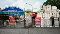 Seorang wanita mendorong kotak styrofoam kosong untuk membuat barikade improvisasi untuk membatasi pergerakan warga di Hanoi, Vietnam pada 30 Agustus 2021. Tiang bambu, peti bir, tangga dan kursi rusak: benda sehari-hari membentuk barikade sementara saat lockdown Covid-19. (Manan VATSYAYANA/AFP)