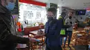 Seorang pria menjalani pemeriksaan kartu vaksin covid-19, di sebuah restoran di Lille, Prancis utara, Senin (24/1/2022). Aturan yang mulai berlaku pada hari Senin mewajibkan “vaksin pass” bagi warga yang ingin mengakses tempat publik. (AP Photo/Michel Spingler)