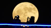 Pasangan berfoto di jembatan Al-Shuhada'a di atas Sungai Tigris saat supermoon pertama tahun 2023 terbit di Baghdad, Irak, Senin, 3 Juli 2023. (AP Photo/Hadi Mizban)