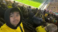 Mahasiswa Indonesia di Dortmund, Amirshah Muhammad Ghifary, sempat merasakan luar biasanya atmosfer Stadion Signal Iduna Park di sela-sela kesibukannya menimba ilmu. Mahasiswa asal Surabaya yang juga pendukung Persebaya Surabaya dan Timnas Indonesia ini juga merupakan pecinta berat olahraga sepak bola. (Bola.com/Dok Pribadi Amirshah Muhammad Ghifary)