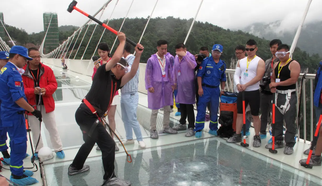 Seorang pria memukulkan palu untuk mencoba kekuatan kaca yang dipakai untuk jembatan di Provinsi Hunan, Cina, (25/6). Jembatan sepanjang 430 meter tersebut terbuat dari bahan kaca. (REUTERS / Jimmy Guan)