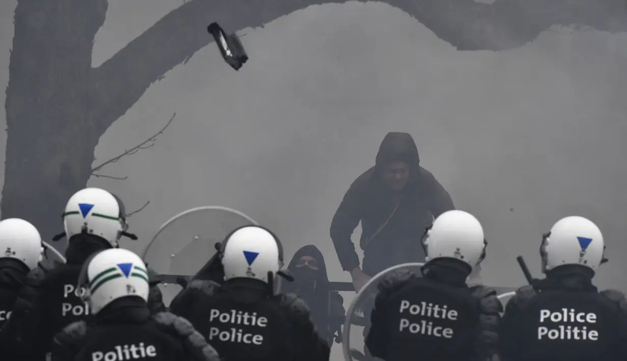 Sebuah proyektil dilempar ke udara saat polisi menghadapi pengunjuk rasa yang menentang tindakan COVID-19 di Brussels, Minggu (23/1/2022). Aksi demonstrasi tersebut berujung ricuh di mana bentrok antara pengunjuk rasa dan polisi tak terhindarkan. (AP Photo/Geert Vanden Wijngaert)