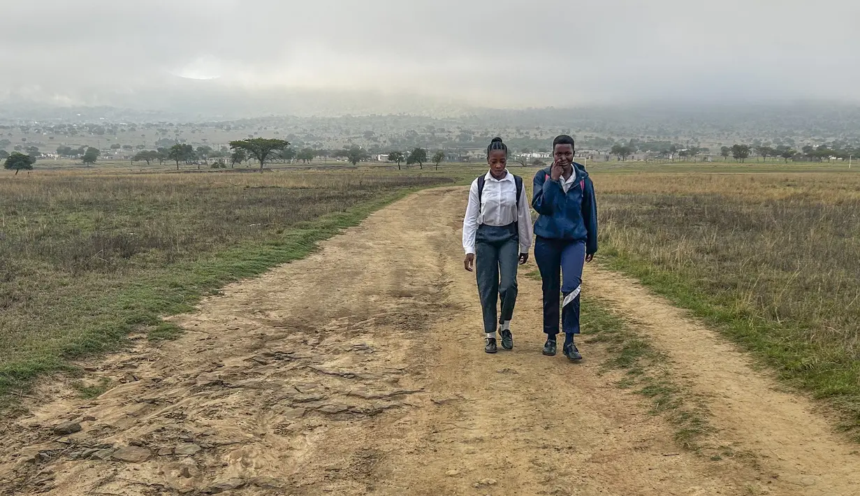 Luyanda Hlali (kiri) dan temannya Mimi Dubazane memulai rutinitas berjalan kaki selama 2 jam dari desa Stratford ke sekolah mereka di Dundee, Afrika Selatan, Kamis, 26 Oktober 2023. (AP Photo/ Mogomotsi Magome)