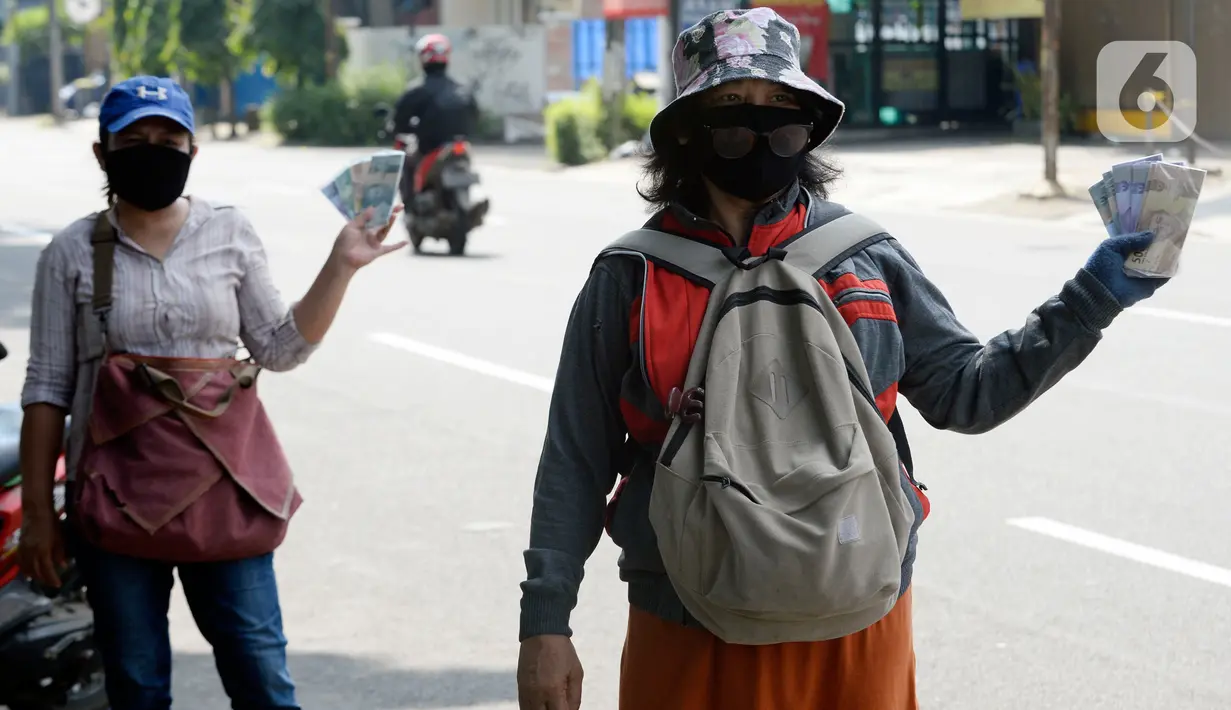 Penjual jasa penukaran uang menawarkan uang baru berbagai pecahan kepada pengguna jalan di kawasan Bintaro Sektor 2, Jakarta Selatan, Selasa (12/05/2020). Pembeli uang kertas baru yang biasanya ramai menjelang Lebaran, kini sepi di tengah pandemi virus corona Covid-19. (merdeka.com/Dwi Narwoko)