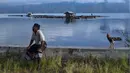 Seorang pria duduk di samping ayam jantan di danau Laut Tawar di Takengon, Aceh tengah, (1/3). Disisi barat danau ini terdapat sebuah kota kabupaten yaitu kota Takengon, yang juga merupakan ibu kota Kabupaten Aceh Tengah. (AFP Photo/Chaideer Mahyuddin)