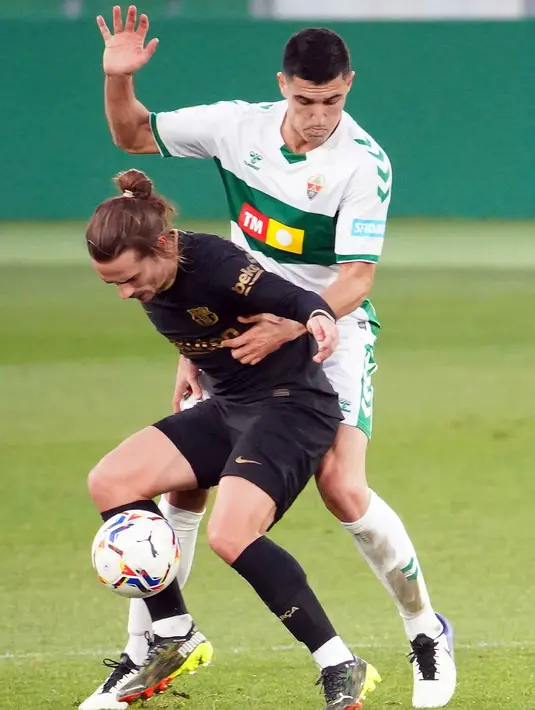 Gelandang Barcelona, Antoine Griezmann (kiri) berebut bola dengan bek Elche, Diego Gonzalez pada lanjutan Liga Spanyol di Stadion Martinez Valero, Elx, Spanyol, Minggu malam WIB (24/1/2021). Barcelona menang 2-0 atas Elche lewat gol yang dicetak Frenkie de Jong dan Riqui Puig. (JOSE JORDAN/AFP)