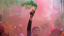 Seorang buruh mengangkat tongkat asap selama unjuk rasa Hari Buruh Internasional (May Day) di Jakarta, Indonesia, Senin (1/5/2023). (AP Photo/Dita Alangkara)