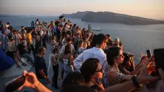 Wisatawan menunggu matahari terbenam di desa Oia di pulau Santorini, Yunani pada 20 Juli 2024. (Aris Oikonomou / AFP)