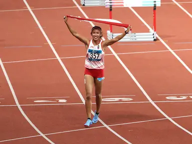Pelari Indonesia, Nova Emilia membawa bendera merah putih usai finis di urutan kedua setelah pelari Korea Selatan Jung Hyelim pada final atletik nomor lari halang rintang 100 meter putri di Stadion Utama GBK, Jakarta (26/8). (Liputan6.com/Fery Pradolo)