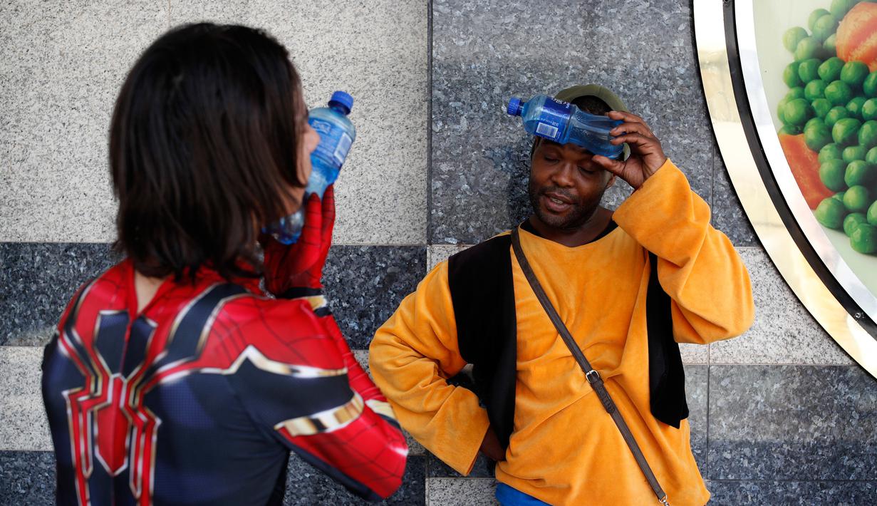 Matthew Santos (kiri) dan Anthony Welch mendinginkan diri dengan botol-botol air dingin di Las Vegas, Amerika Serikat, Rabu (25/7). Sejumlah gurun di Barat Daya menguatkan panas yang ekstrem. (AP Photo/John Locher)