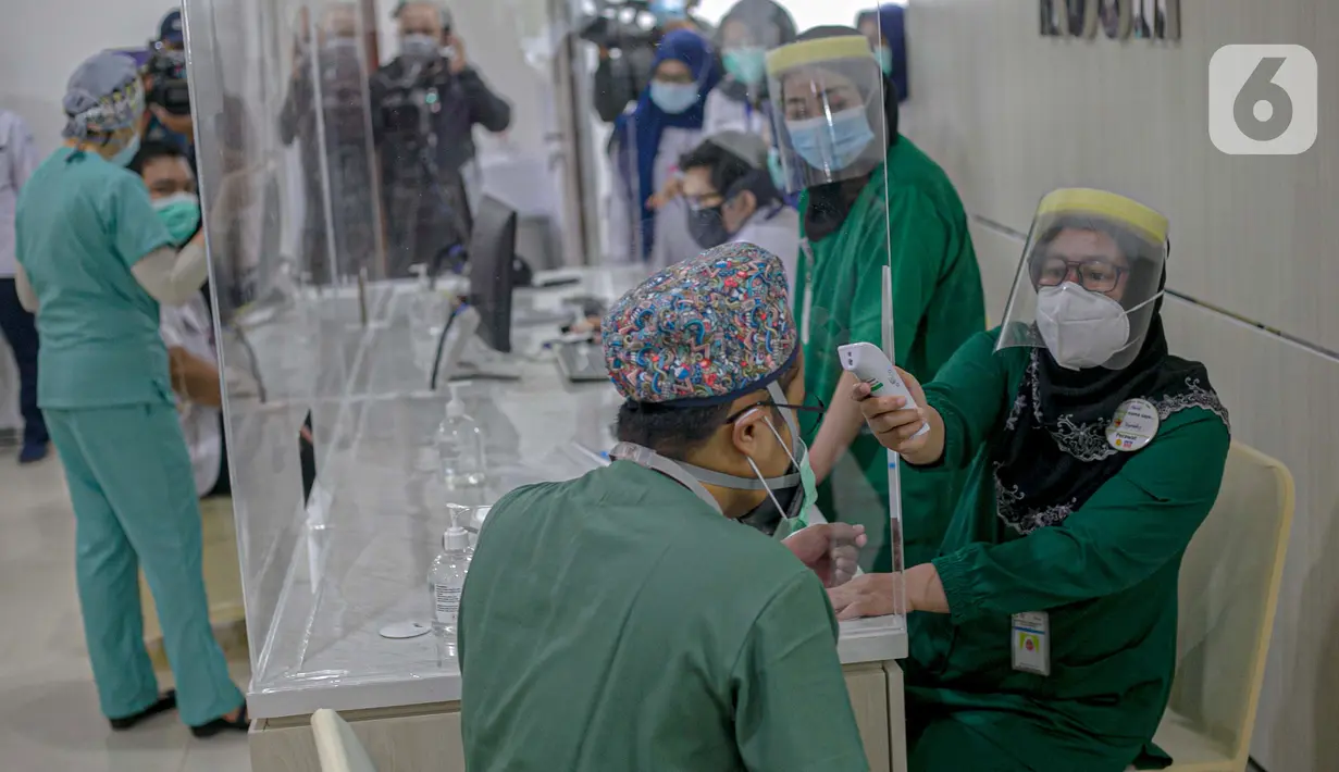 Tenaga kesehatan menjalani pengecekan suhu tubuh sebelum disuntik vaksin virus corona COVID-19 di RSCM, Jakarta, Kamis (14/1/2021). Vaksinasi COVID-19 tahap awal akan menargetkan 1,48 juta tenaga kesehatan. (Liputan6.com/Faizal Fanani)
