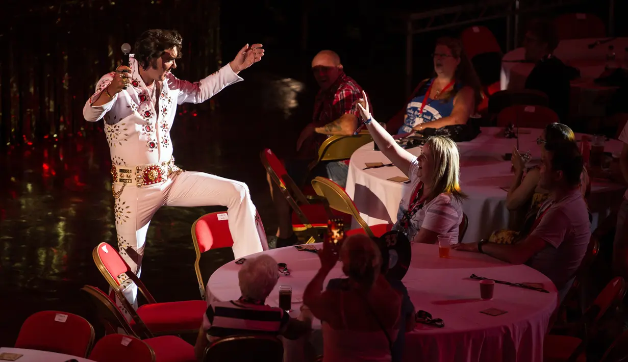 Penyanyi Jason Dale berinteraksi dengan penonton saat tampil dalam pembukaan 'Perayaan Elvis 2018' di Blackpool Winter Gardens, Barat Laut Inggris, Jumat (29/6). Peringatan Elvis Presley ini dihadiri artis, pedagang, dan para penggemar. (Oli SCARFF/AFP)