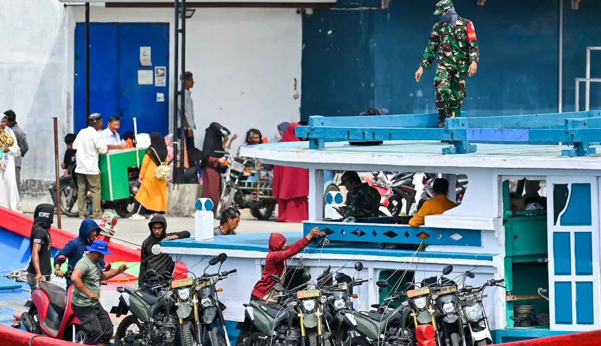 Seorang tentara mengawasi para pekerja yang sedang memuat bahan pemilu ke sebuah kapal menuju pulau-pulau terpencil, di Pulo Aceh, di Banda Aceh pada 12 Februari 2024. (CHAIDEER MAHYUDDIN/AFP)