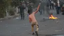 Seorang demonstran antipemerintah melemparkan batu ke arah pasukan keamanan saat protes di dekat Alun-Alun Tahrir, Baghdad, Irak, Senin (27/7/2020). Perdana Menteri Irak mengatakan telah memerintahkan penyelidikan atas pembunuhan dua demonstran antipemerintah. (AP Photo/Hadi Mizban)