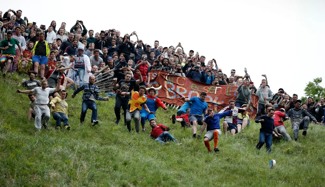 Puluhan orang berlomba mengejar gulungan keju dalam kompetisi Cheese Rolling di Brockworth, Gloucestershire, Inggris, 30 Mei 2016. Persaingan dimulai setelah keju yang berbentuk seperti roda digelindingkan dari puncak bukit. (Adrian DENNIS/AFP)