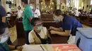 Petugas kesehatan menyuntik seorang perempuan dengan vaksin COVID-19 produksi AstraZeneca di dalam gereja Paroki Hati Kudus Yesus di Quezon City, Filipina, Senin (17/5/2021). Gereja itu digunakan untuk mempercepat proses vaksinasi kepada warga di daerah tersebut. (AP Photo/Aaron Favila)