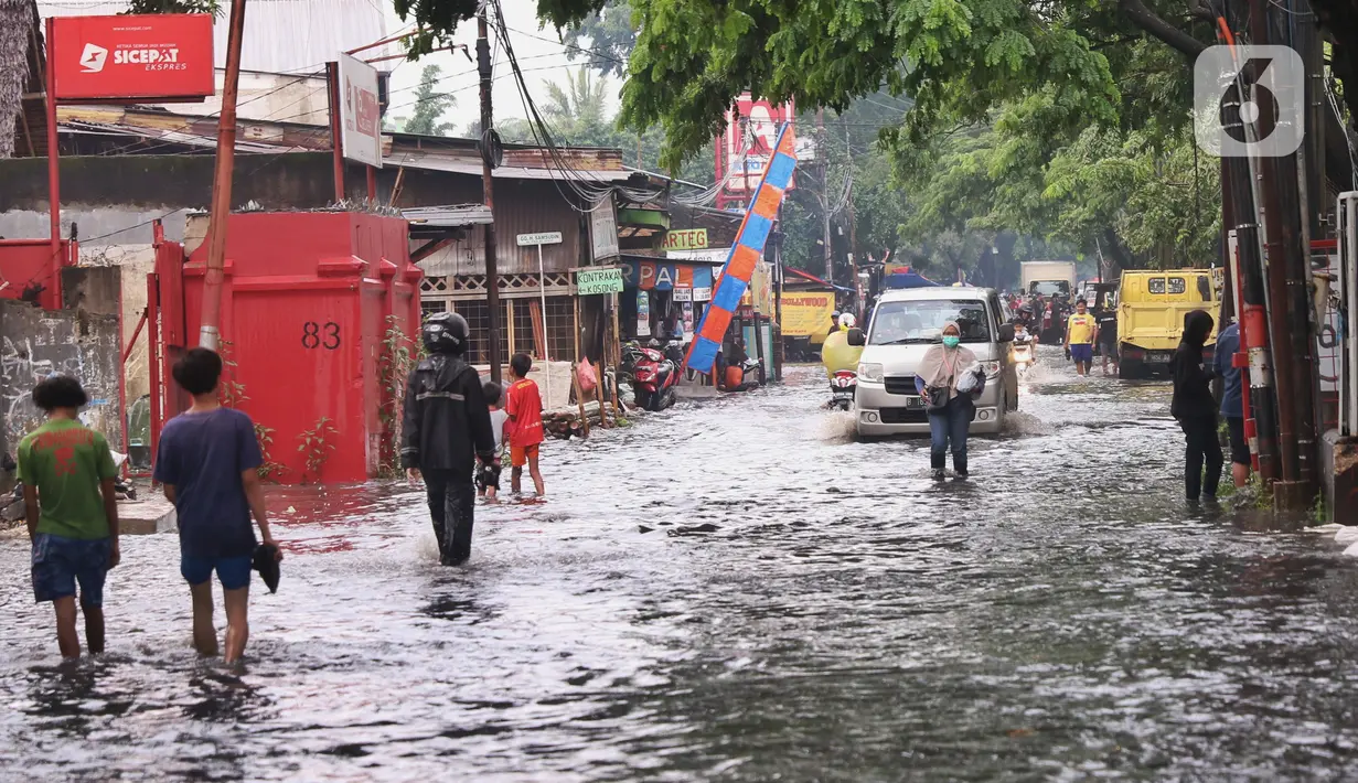 Aktivitas warga saat banjir merendam Jalan KH. Ahmad Dahlan Cipondoh, Tangerang, Selasa (16/2/2021). Hujan deras yang melanda wilayah Tangerang mengakibatkan ruas jalan alternatif penghubung Tangerang dengan Jakarta tersebut banjir setinggi lutut orang dewasa. (Liputan6.com/Angga Yuniar)
