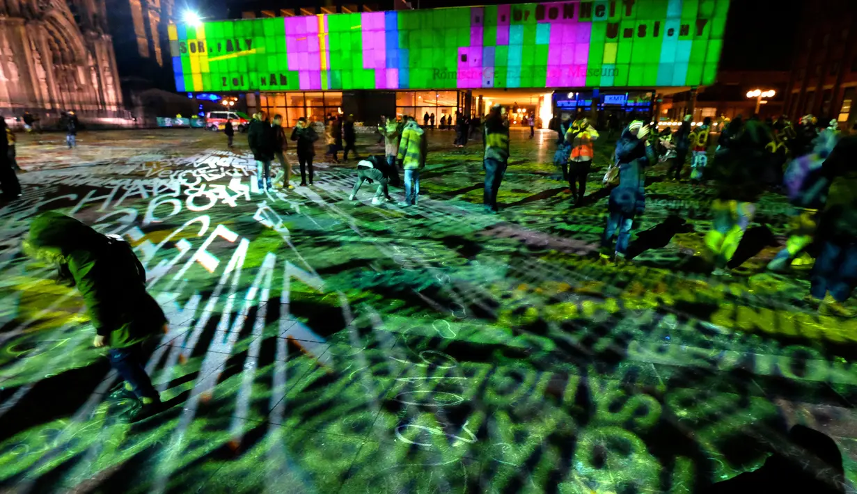 Sejumlah pengunjung menikmati instalasi cahaya jelang pergantian tahun di Cologne, Jerman (31/12). Instalasi cahaya tersebut berbentuk macam-macam tulisan yang berkilauan. (AFP/Patrik Stollarz)