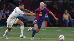 Pemain Barcelona, Dani Olmo (kanan) berebut bola dengan pemain Valladolid, Javi Sanchez pada laga lanjutan Liga Spanyol 2024/2025 di Olympic Stadium, Barcelona, Spanyol, Sabtu (31/08/2024). (AP Photo/Joan Monfort)